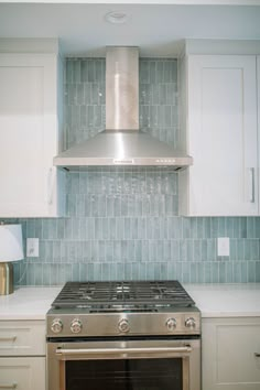 a stove top oven sitting inside of a kitchen next to white cabinets and counter tops