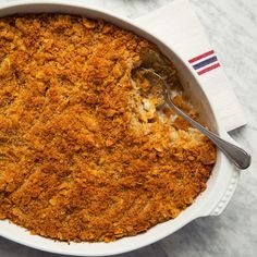 a casserole dish with a spoon in it sitting on a white tablecloth