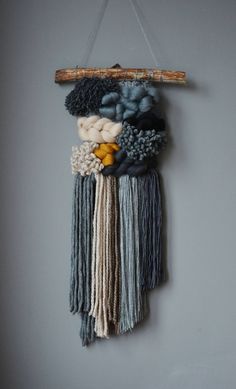 a piece of art hanging on the wall with yarn and wood sticks attached to it