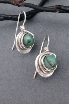 Raw genuine green emerald gemstones, weighing 1.8 carats each (3.6 carats/pair), are wrapped in sterling silver wire, then set within a sterling round dangle. Ear wires are also handcrafted in sterling silver wire. Artisan elegance and lightweight design make these earrings perfect for all day wear Green Sterling Silver Dangle Jewelry, Green Teardrop Sterling Silver Jewelry, Green Sterling Silver Wire Wrapped Jewelry, Sterling Silver Wire Wrapped Jewelry For Anniversary, Green Wire Wrapped Sterling Silver Jewelry, Green Wire Wrapped Silver-plated Jewelry, Wire Wrapped Green Sterling Silver Jewelry, Unique Green Sterling Silver Jewelry, Elegant Wire Wrapped Earrings For May Birthstone