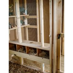 a large chicken coop with several cages on the wall and one door open to let birds in