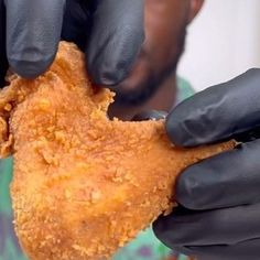 a man in black gloves is eating some fried food with his hands on the plate