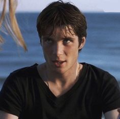 a young man holding a frisbee near the ocean