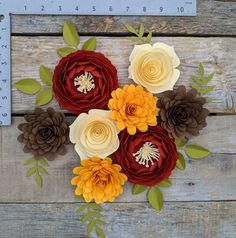 paper flowers are arranged on top of a piece of wood with a ruler in the background