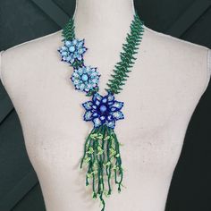 a blue and green flowered necklace on a mannequin's back neck