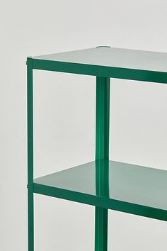 a green shelf with two shelves on one side and a white wall in the background