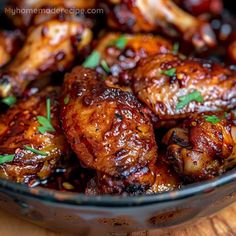 chicken wings with cranberry sauce and parsley in a glass bowl on a wooden table