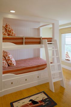 bunk beds with ladders and pillows in a white painted room, along with a rug on the floor