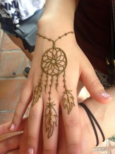 a woman's hand with hennap on it and a dream catcher tattoo