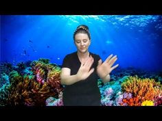 a woman is standing in front of an underwater scene with her hands up to the air