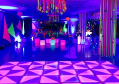 the dance floor is lit up with neon lights and decorations for an elegant party or event