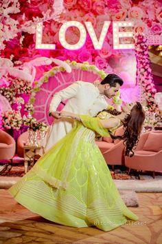 a man and woman dancing in front of a love sign