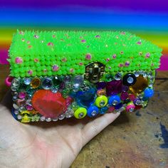 a hand holding a green case with lots of beads on it