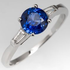 This blue sapphire ring is centered with a 1.16 carat round cut sapphire in a four-prong setting. The shoulders are each channel set with one tapered baguette cut diamond. This is a recently sourced sapphire of Madagascar origin that EraGem set into this mounting. The sapphires color is a very impressive rich blue. The ring is currently a size 7.25 and we offer complimentary resizing to fit. Engagement Rings Blue, Gem Engagement Rings, Green Montana, Rings Blue, Engagement Ring Platinum, Sapphire Engagement Rings, Blue Sapphire Engagement Ring, Blue Engagement Ring, Art Deco Diamond Rings