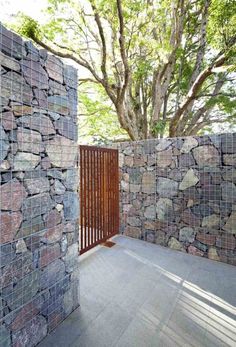 an image of a stone wall and wooden gate with trees in the backgroud