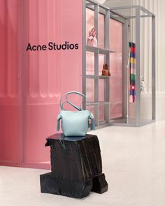 an acne studios store with pink walls and blue handbags