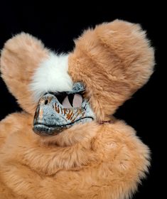 a teddy bear with a mask on it's face and feathers around its eyes