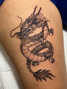 a black and white dragon tattoo on the thigh, it looks like he is ready to strike