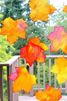 the fall leaves are hanging from the porch railing and in front of the deck, there is an umbrella that has been made out of paper