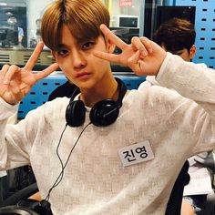 a young man with headphones making the peace sign in front of his ear phones