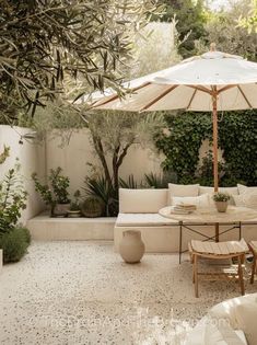 an outdoor living area with couches, tables and umbrellas in the middle of it