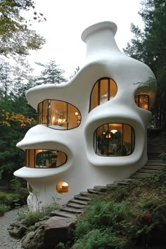 the house is shaped like a mushroom with windows on each side and stairs leading up to it