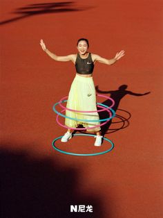 a woman standing on top of a tennis court surrounded by hula hoops in front of her