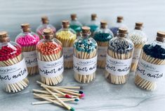 several matches are lined up in bottles with labels on them, and one is filled with different colored matchsticks