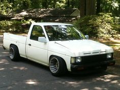 a white pick up truck parked on the side of a road in front of some trees