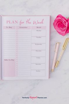 a pink planner and pen next to a rose on a white marble surface with the words plan for the week written in it