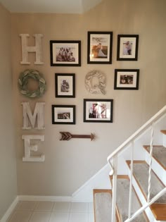 there are many framed pictures on the wall above the stair case, along with an arrow