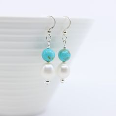 These stunning drop earrings are handmade with round baby blue Kingman Arizona turquoise beads and white pearls that drop from a designer hammered French hook. Available in sterling silver or 14k gold filled. The turquoise beads are 8mm round, the pearls are 10mm ovals, and spaced with flat sterling silver beads. The turquoise used for these earrings is from Kingman Turquoise Mine in Kingman Arizona.  Length from the top of ear wire: 1.75" Color: Baby blue with some honey brown matrix Gemstone: Adjustable Blue Pearl Drop Jewelry, Handmade Blue Dangle Pearl Earrings, Handmade Blue Sterling Silver Pearl Earrings, Turquoise Pearl Dangle Earrings, Handmade Blue Pearl Earrings In Sterling Silver, Handmade Blue Pearl Earrings, Turquoise Pearl Drop Jewelry, Blue Pearl Dangle Earrings, Handmade Turquoise Dangle Pearl Earrings