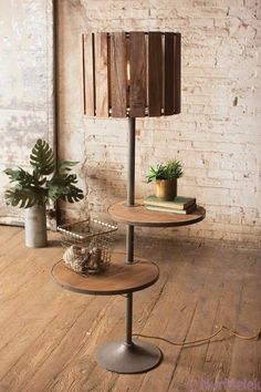 two tiered tables with plants on them in front of a brick wall and wooden floor