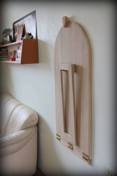 a wall mounted coat rack in a living room next to a white leather chair and book shelf