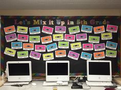 three computer monitors sitting on top of a desk next to each other in front of a blackboard