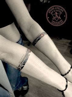 two people with tattoos on their legs sitting next to each other and holding hands together