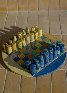 a colorful chess board with blue and yellow vases on the table next to it