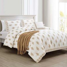 a bed with white and gold comforters in a room