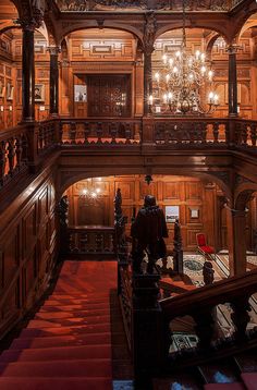 an ornate wooden building with chandeliers hanging from the ceiling and red carpeted stairs