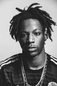 a black and white photo of a man with dreadlocks on his head, wearing a t - shirt