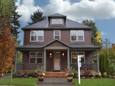 a brown house with lots of windows and plants on the front lawn in front of it