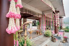 an outdoor wedding venue with pink and white flowers hanging from the ceiling, along with other decorations