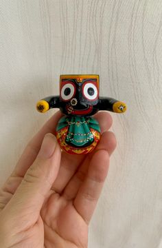 a hand holding a small figurine with eyes