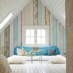 a room with blue and white striped walls, wood flooring and a couch in the corner