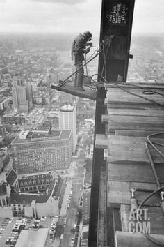 a man standing on top of a tall building next to a sky scraper in the city