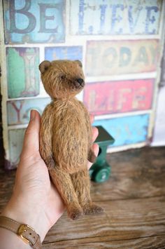 a person holding a small teddy bear in their hand