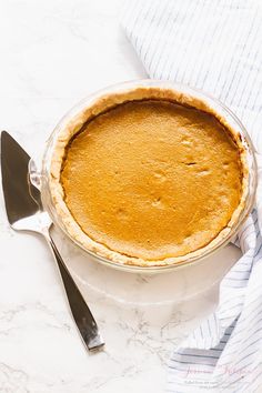 a pie sitting on top of a white table next to a knife and fork,