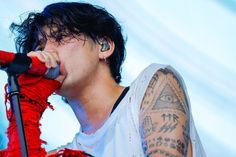 a man with tattoos on his arm singing into a microphone