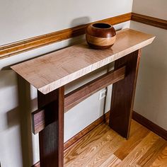 a wooden bowl sitting on top of a table next to a wall with wood trim