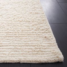 a large white rug on top of a hard wood floor next to a black wall